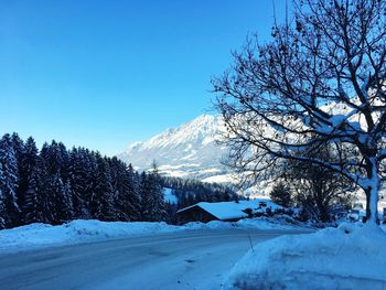 Snow covered landscape against clear blue sky