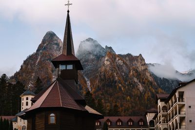 Panoramic view of church building and mountains against clouds and sky