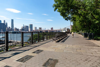 Footpath by buildings in city against sky