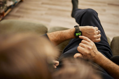 Grandfather using smart watch with granddaughter sitting at home