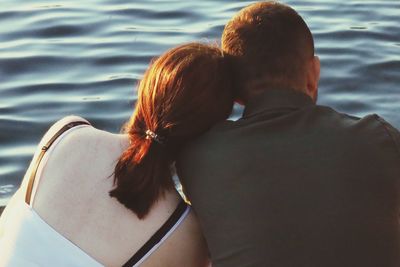 Rear view of couple kissing against water