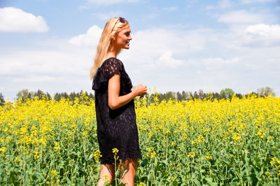 Woman standing on yellow flowering field