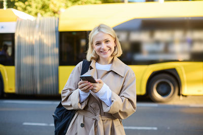 Portrait of young woman standing in car