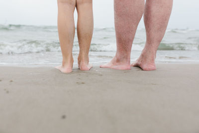Low section of man standing on beach