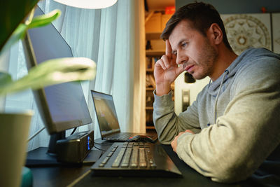 Side view of man using laptop at home