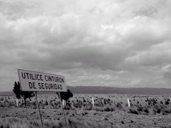 Sign board on beach against sky