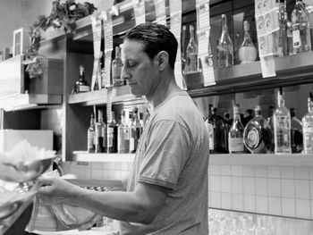 Side view of man standing by glass bottles