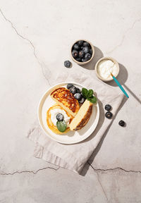 Cottage cheese pancakes served with curd and blueberries, top view flat lay on marble background