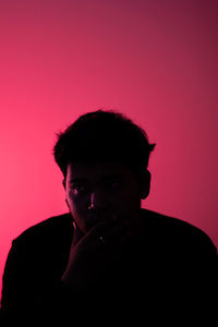 Portrait of young man against red background