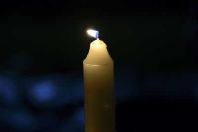 Close-up of illuminated candle in darkroom