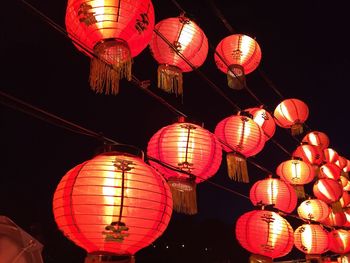 Low angle view of illuminated lanterns hanging against sky at night