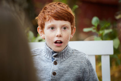 Surprised boy looking away while sitting in yard