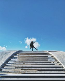Low angle view of man running on staircase against clear sky