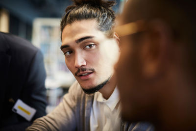 Creative businessman looking at male colleague during meeting in office