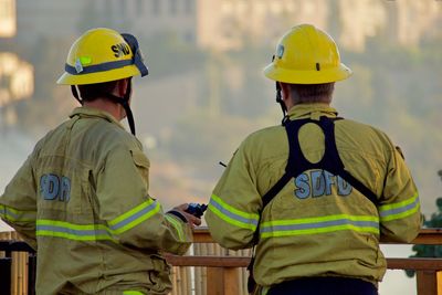 Rear view of firefighters standing by railing