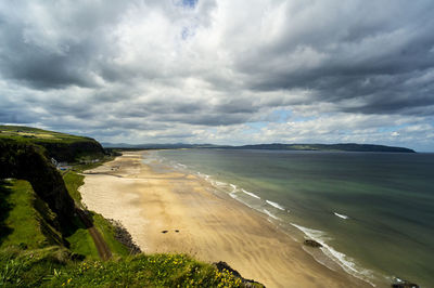 Scenic view of beach against cloudy sky