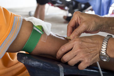 Cropped hands of doctor injecting syringe on hand of patient