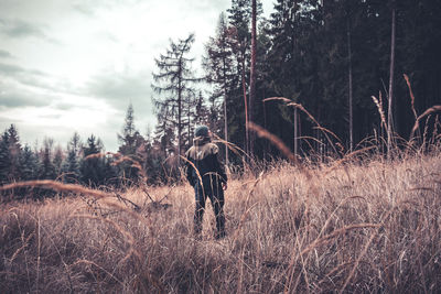 Rear view of man standing on field in forest