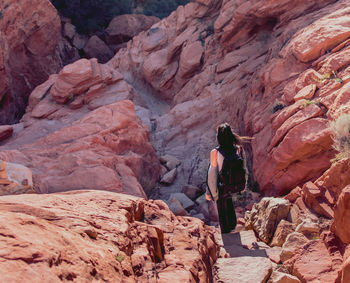 Rear view of woman standing by rock formation