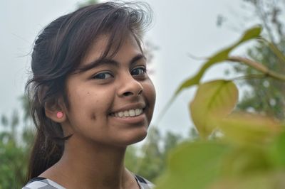 Close-up portrait of smiling girl by plants