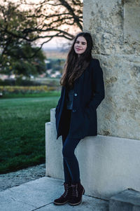 Portrait of smiling young woman standing against tree