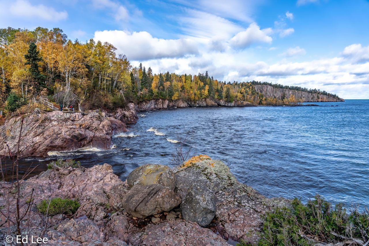 ROCKS BY SEA AGAINST SKY