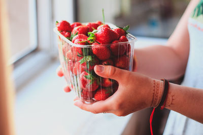 Close-up of hand holding strawberry in container