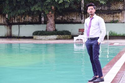 Portrait of man standing by swimming pool