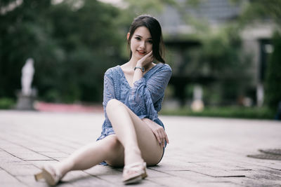 Young woman sitting on footpath
