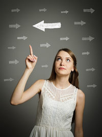 Portrait of young woman standing against black background