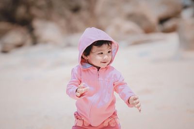 Cute baby girl wearing pink hooded shirt at beach
