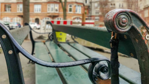 Close-up of metal railing against buildings in city