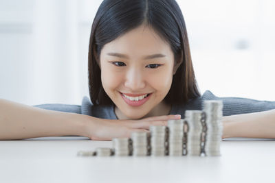 Smiling young woman looking at stacked coins