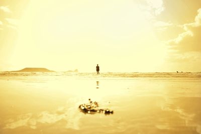 Silhouette man on beach against sky during sunset