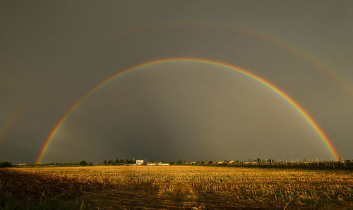 Scenic view of rainbow over field against sky