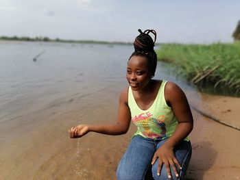 Full length of smiling woman sitting on land