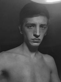Portrait of shirtless young man against black background