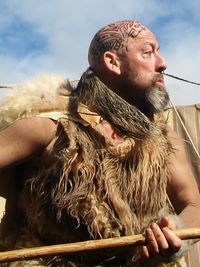 Man in costume looking away while standing against sky