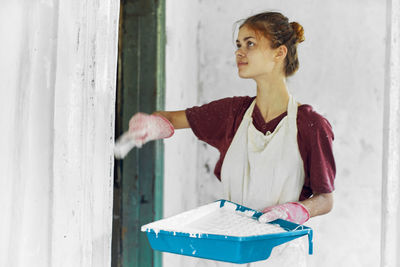 Side view of young woman standing against wall