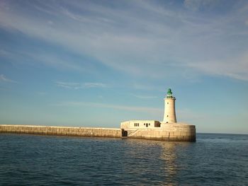 Lighthouse by sea against sky