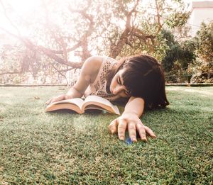 Young woman reading book while lying on grassy field