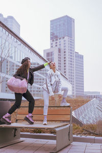 Woman touching friend hair bun against buildings in city