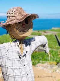 Scarecrow against sea on sunny day
