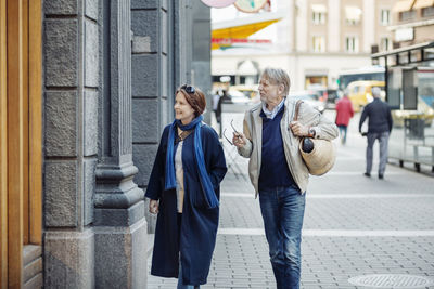 Senior couple looking at store window while walking on city street