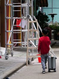 Rear view of man walking on street against buildings