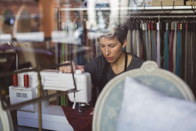 View of tailor working in studio through glass wall