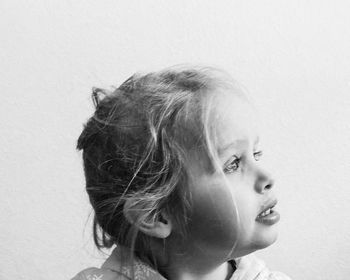 Close-up portrait of a girl looking away against wall