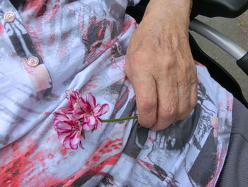 Midsection of woman with flower sitting wheelchair