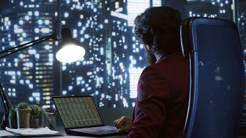 Rear view of man using laptop at home