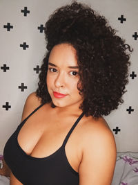 Portrait of young woman standing against wall